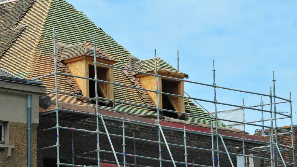 Roof replacement in progress with scaffolding around a steep residential roof