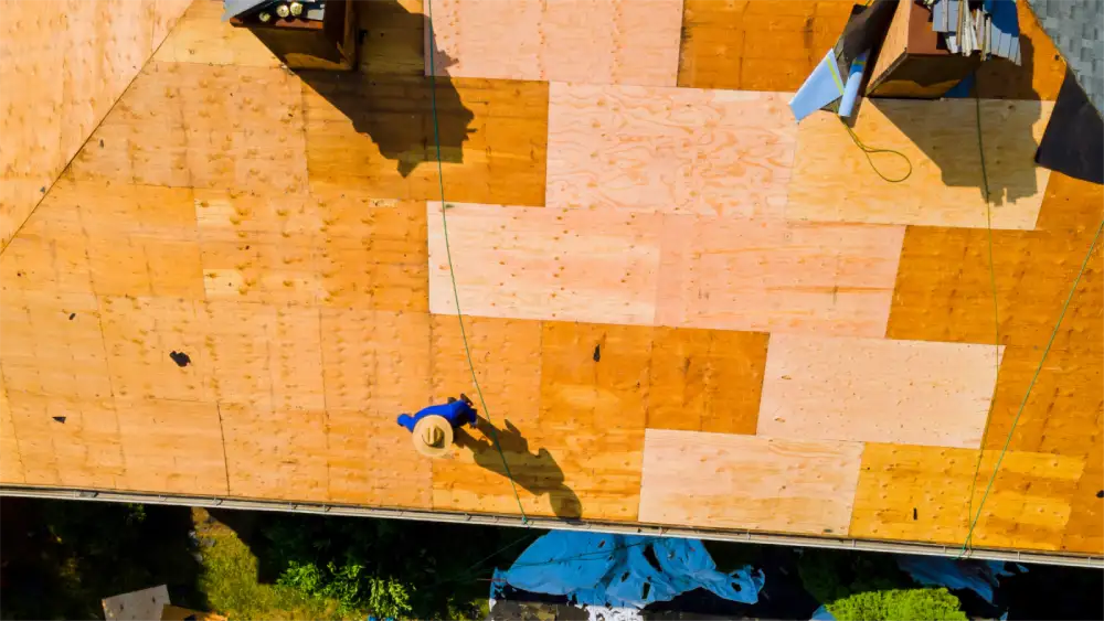 Top view of roofers applying underlayment on a stripped roof surface