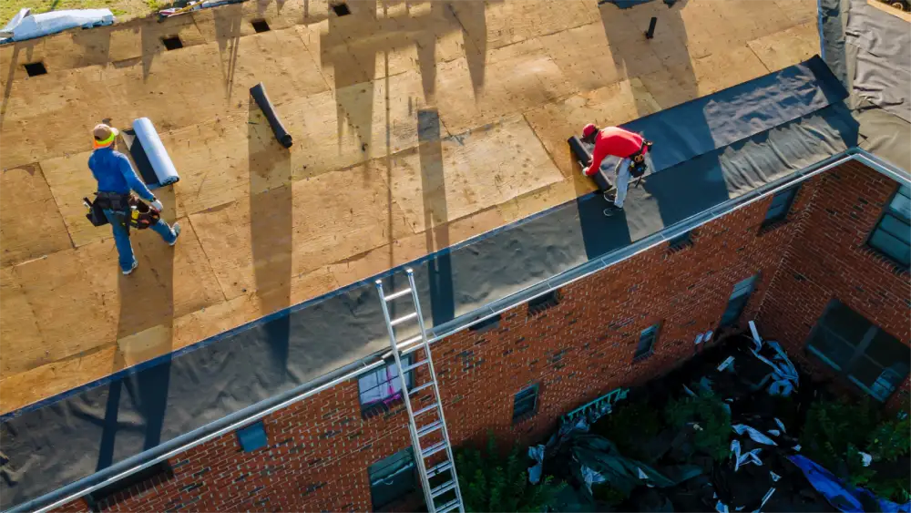 Workers preparing a rooftop with new underlayment for shingle installation